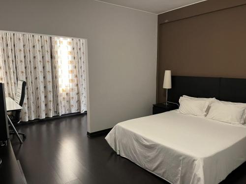 罗安达Casas de Luanda GH-Alvalade的卧室配有白色的床和窗户。