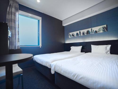 东京Henn na Hotel Tokyo Asakusabashi的一间卧室设有两张床、一张桌子和一个窗口