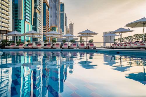 迪拜迪拜罗塔纳大厦酒店的城市里一个带椅子和遮阳伞的游泳池