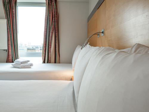伦敦Maiden Oval的配有白色枕头的酒店客房内的两张床
