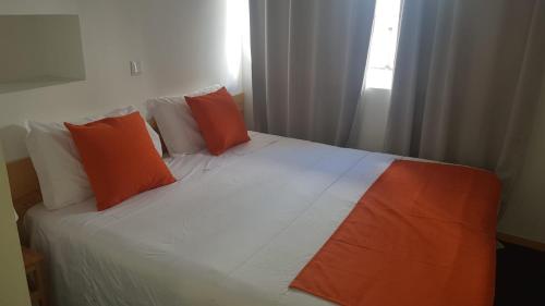 西尔韦斯Al-Xelb guesthouse的一张带橙色和白色枕头的床和窗户