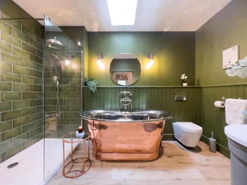 布兰普顿Waters Edge, Talkin Tarn, nr Brampton的浴室设有铜质浴缸,位于绿色的墙壁上