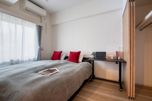 东京Creazione Akasaka的一间卧室配有一张带红色枕头的床和一张书桌