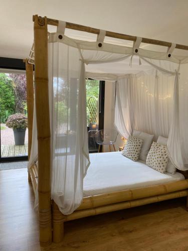 潘蓬L'Hôtié de Brocéliande à Paimpont, au coeur des sites naturels et légendaires的卧室配有带白色窗帘的天蓬床