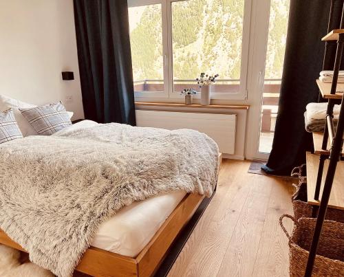萨斯费Appartment Alpenrose的一间卧室配有一张带白色毯子的床和窗户。