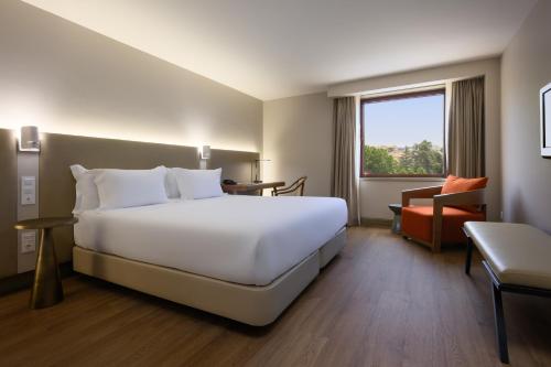科英布拉Hotel Coimbra Aeminium, Affiliated by Meliá的酒店客房带一张大床和一把椅子