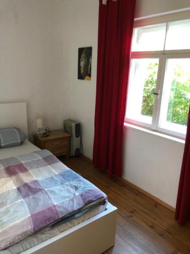 慕尼黑Schöne Wohnung Nahe Engl. Garten的一间卧室配有床和红色窗帘的窗户
