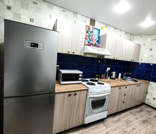 巴甫洛达尔Уютная трёхкомнатная квартира的厨房配有不锈钢冰箱和木制橱柜