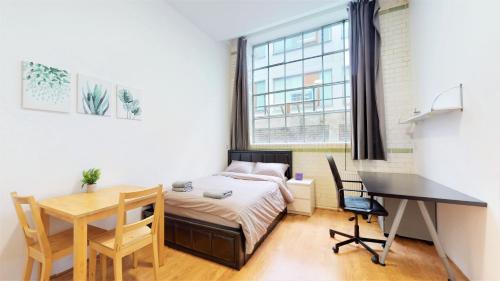 伦敦Amazing Studio Apartment的一间卧室配有一张床、一张桌子和一张桌子