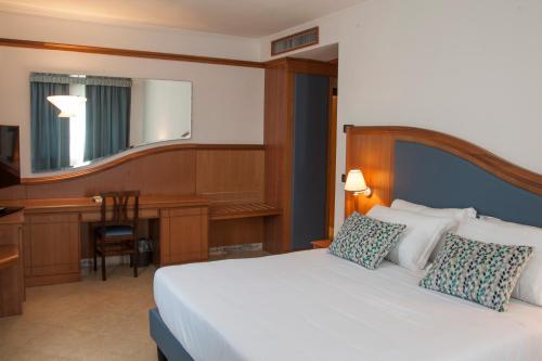 萨包迪亚Hotel Centrale的卧室配有一张白色的床、一张桌子和一台电脑