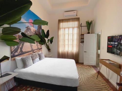 巴拿马城AmazINN Places Boutique Casa Arias的卧室配有白色的床和墙上的绘画作品