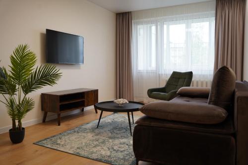 帕内韦日斯Sonata apartment的客厅配有沙发、椅子和电视