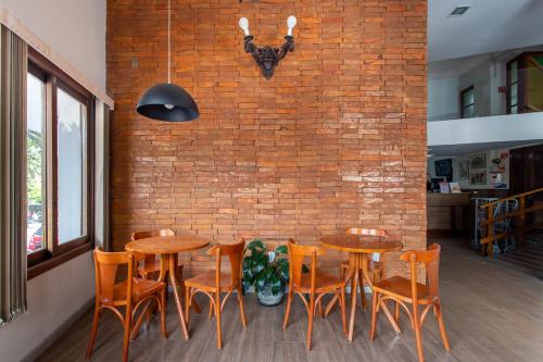 圣玛丽亚Hotel Dom Rafael Express的一间设有木桌椅的用餐室和砖墙