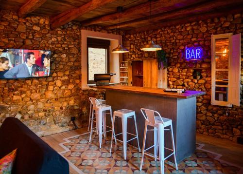 ENTREPIEDRAS的酒吧设有凳子,石墙上配有电视