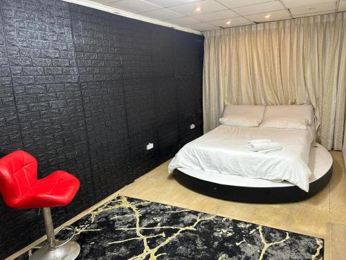 海法לאון ספא לופט - חדרי אירוח עם בריכה פרטית וסאונה בלב חיפה的一间卧室配有一张床和一张红色椅子
