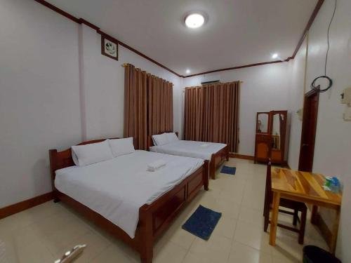 万荣Inthavong Hotel/Guest House的一间卧室配有两张床和一张桌子