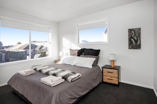 基督城Spacious Quality Apartment, Convenient Location的一间卧室设有一张大床和两个窗户。