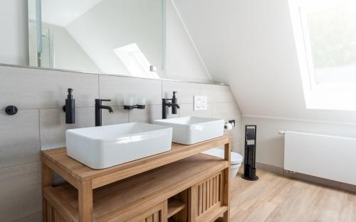 诺伊鲁平Up Hus Hotel Neuruppin的浴室设有木台上的两个盥洗盆