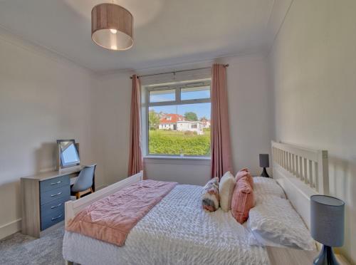 西基尔布赖德Seamill Cottage的一间卧室设有一张大床和一个窗户。