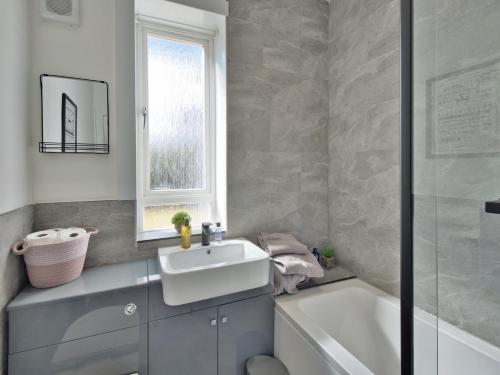 西基尔布赖德Seamill Cottage的一间带水槽和浴缸的浴室以及窗户。