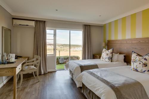 斯泰伦博斯Protea Hotel by Marriott Stellenbosch & Conference Centre的酒店客房设有两张床、一张书桌和一个窗户。