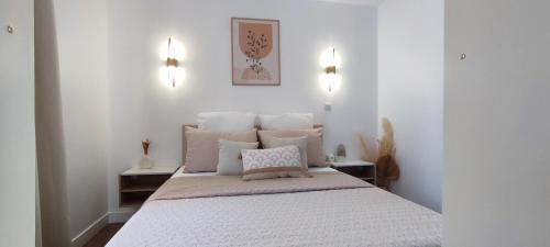 格里莫Chez Adriana Appartement Cosy avec Jardin, proche plage的卧室配有一张带白色床单和枕头的大床。
