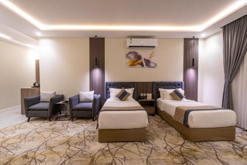 利雅德فندق هوليداي الخليج النجاح的酒店客房,配有两张床和两把椅子