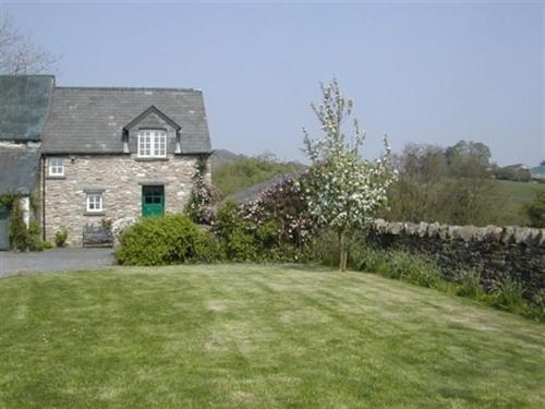 布雷肯Alltybrain Farm Cottages and Farmhouse B&B的一座石头房子,设有绿门和庭院