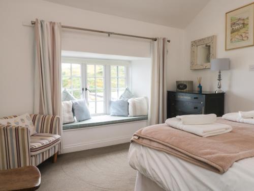 波特洛Kerbenetty Harbour Cottage的一间卧室设有两张床和一个带椅子的窗户。