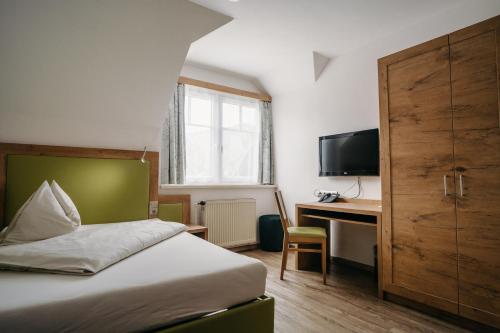 弗里萨赫托马汉旅馆的一间卧室配有一张床、一张书桌和一台电视
