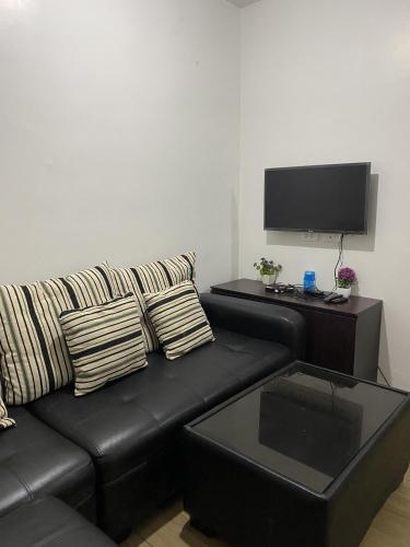 大雅台Alitheia Condo @ Pine Suites Tagaytay的客厅配有黑色沙发和平面电视。