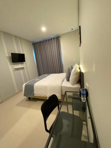 雅加达Ghurfati Hotel Wedana的酒店客房设有一张床铺和一张玻璃桌