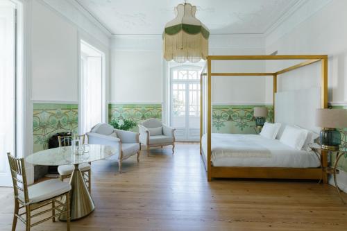 里斯本Palácio do Visconde - The Coffee Experience的一间卧室配有天蓬床和桌椅