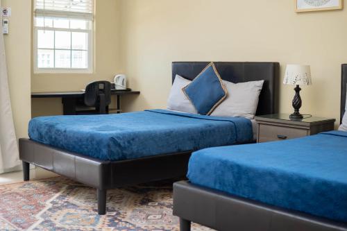 圣玛丽GC Resort的一间卧室配有两张带蓝色床单的床和一张书桌