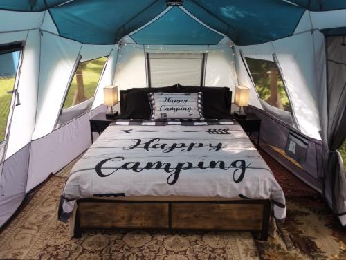 WashagoGlamping on the Green River的帐篷内的一张床位,上面有快乐的露营标志