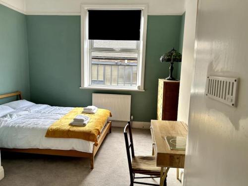 哈罗盖特Suze's Stays的一间卧室配有一张床、一张桌子和一个窗户。