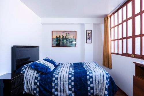 库斯科Casa de Laura的一间卧室配有一张带蓝色棉被的床和窗户。