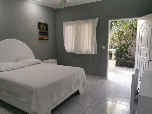 纳瓜坎布里酒店的卧室配有白色的床和窗户。