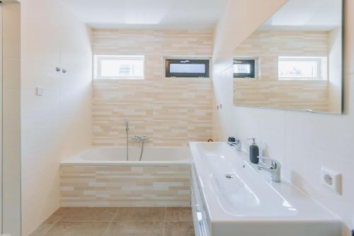 阿姆斯特丹Brand new bright luxurious villa in Amsterdam!的带浴缸、水槽和镜子的浴室