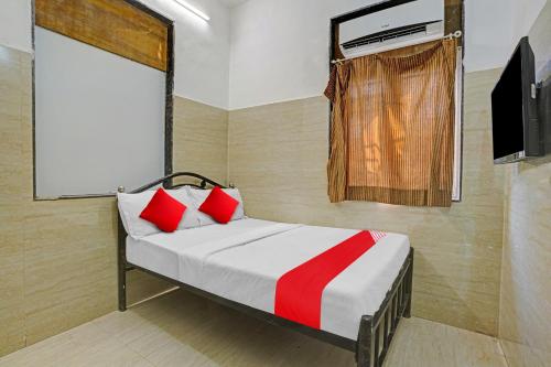 孟买OYO Flagship Raj Hotel Near Juhu Beach的一间卧室配有一张带红色枕头的床和一台电视。