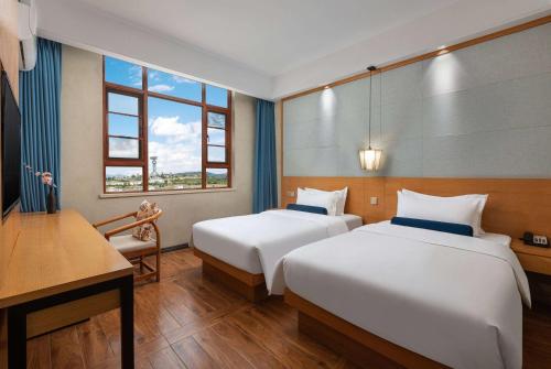 大理大理洱海公园戴斯精选温德姆酒店的酒店客房设有两张床、一张书桌和窗户。