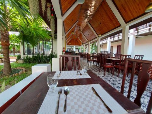 琅勃拉邦Sunrise Garden House - Luang Prabang的一间设有桌椅和树木的餐厅
