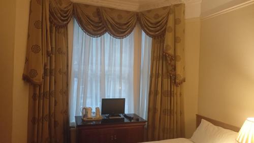 伦敦赛古酒店的一间卧室设有一张床和一个带显示器的窗户