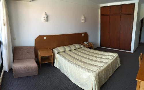 珀彻斯Albergaria Dom Manuel Hotel的一间卧室配有一张床、一把椅子和一个橱柜
