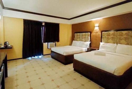 CangbaliguiaRedDoorz at Carlton-Martin Hotel Masbate City的酒店客房设有两张床和窗户。