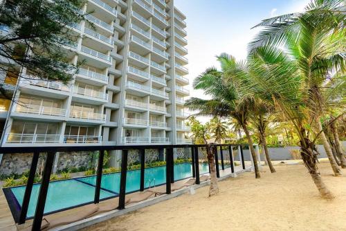 贾埃勒MaSa Beach Front Apartment Uswetakeiyawa的一座大型公寓楼,设有游泳池和棕榈树