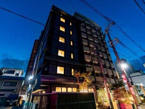 NishinotōindōriTabist kiki HOTEL KYOTO Gojo Karasuma的黑夜高大的建筑,灯火通明