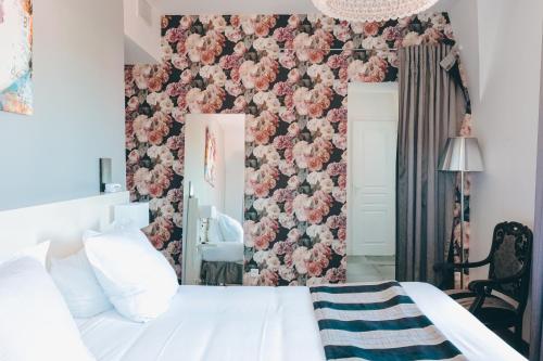 拉罗谢尔Le Manoir Hôtel的卧室配有白色的床和粉红色花卉墙
