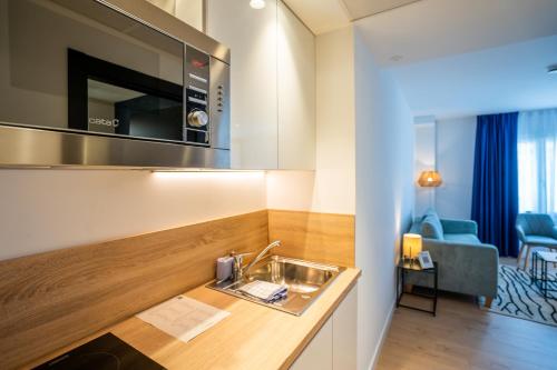 圣塞瓦斯蒂安abba Apartments Playa de Gros San Sebastián的一个带水槽的厨房和一间客厅