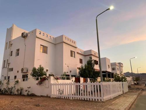 达哈布Dahab Relax Studio 3的白色的建筑,有白色的栅栏和街灯